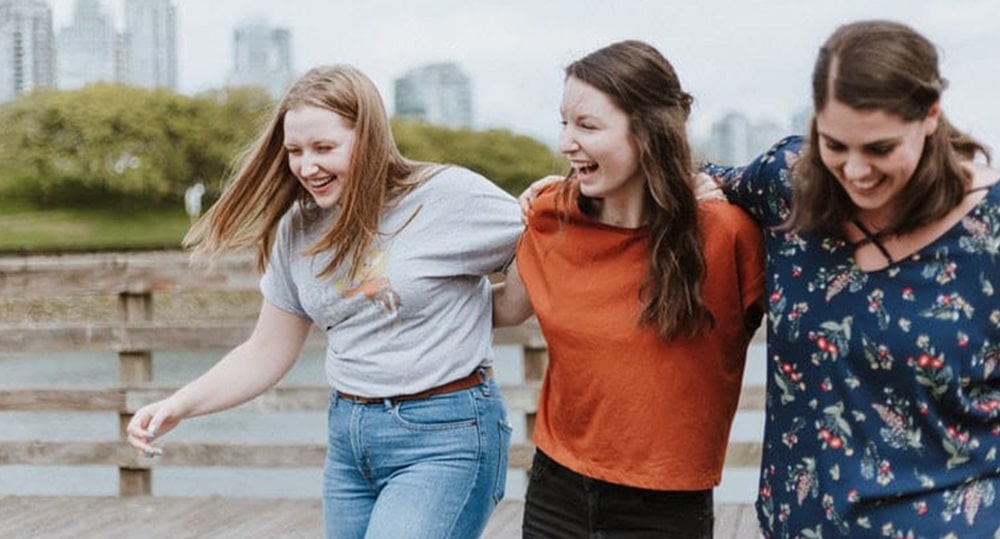 Three friends laughing together on a walk