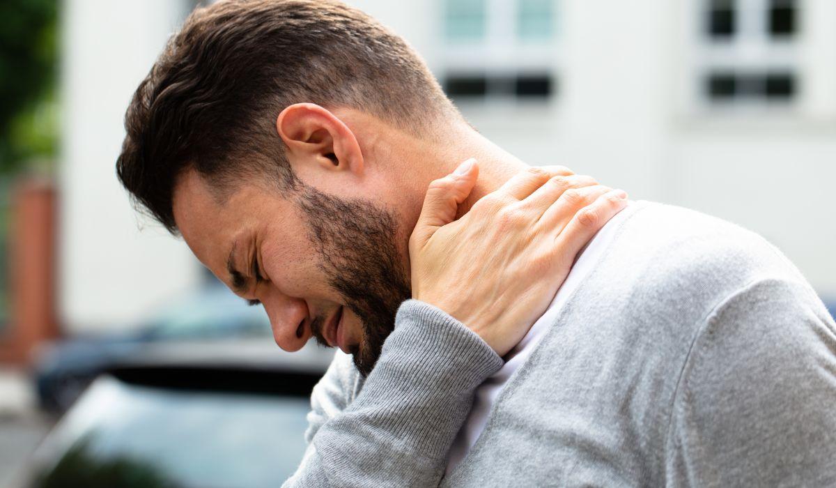 Man wincing and holding his stiff neck